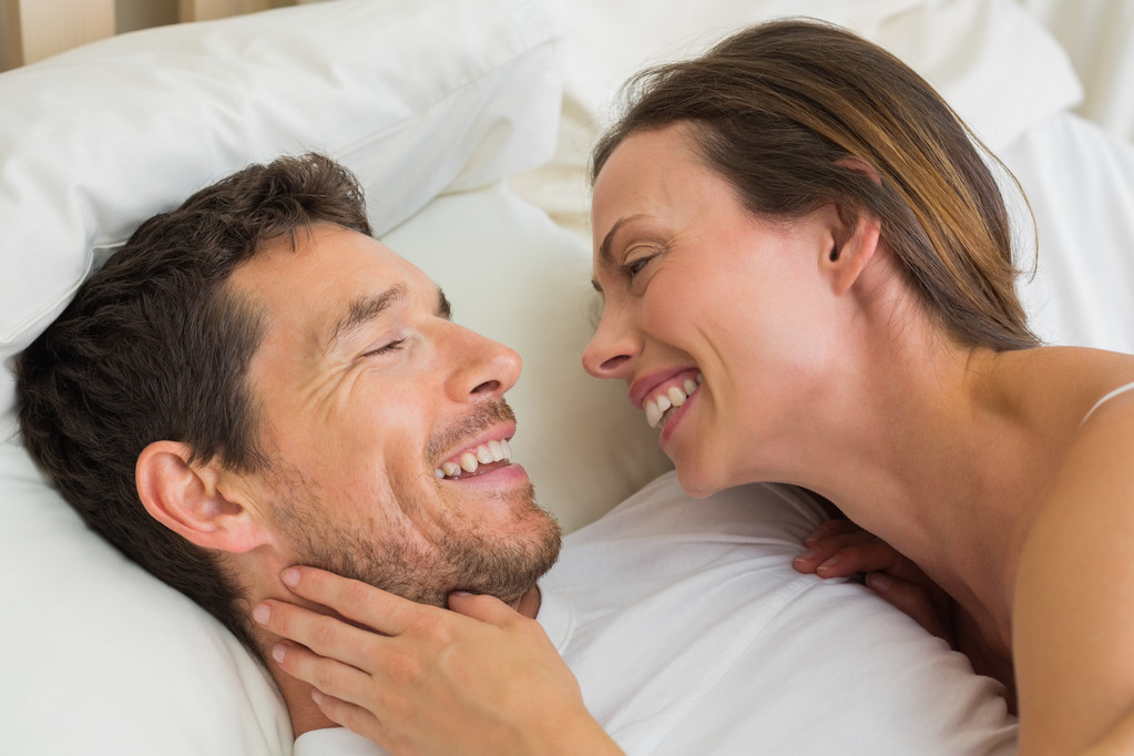 Close-up of a cheerful young couple lying together in bed at home